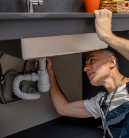 Technicien inspectant une canalisation sous un évier