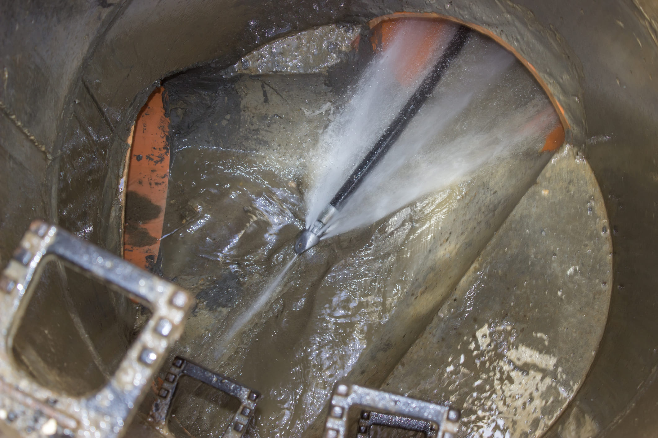 Vue intérieure d'une canalisation où un jet d'eau haute pression nettoie les parois, technique professionnelle de débouchage.