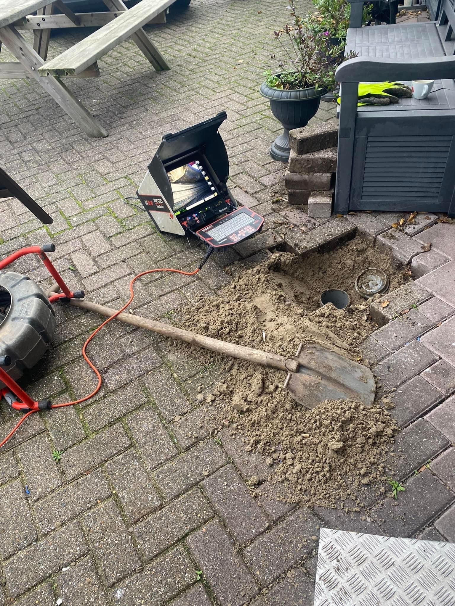 Inspection de canalisation en cours avec caméra endoscopique, montrant un écran de surveillance près d'une excavation extérieure, outil de diagnostic professionnel pour les tuyaux