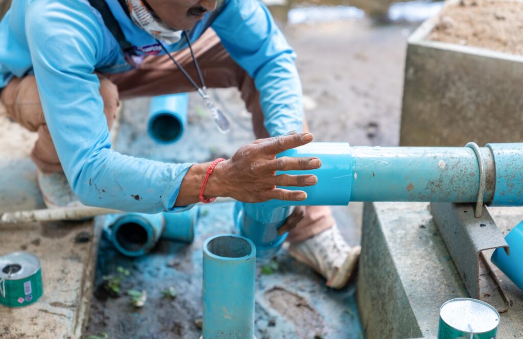 Un professionnel assemble des tuyaux en PVC, une installation qui pourrait également bénéficier du chemisage de canalisation pour une réparation rapide et durable des canalisations existantes.